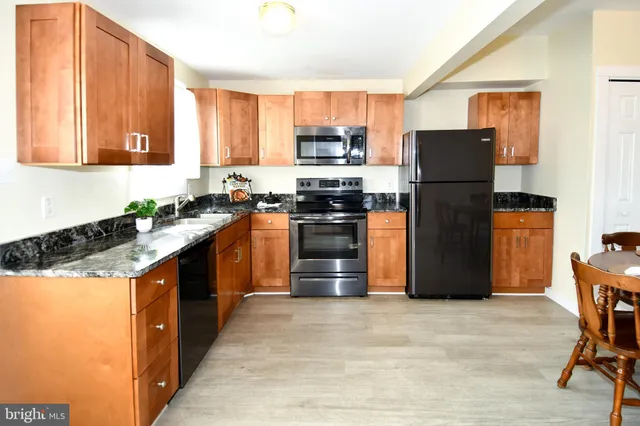 a kitchen with stainless steel appliances granite countertop a stove a refrigerator and a sink dishwasher with wooden cabinets