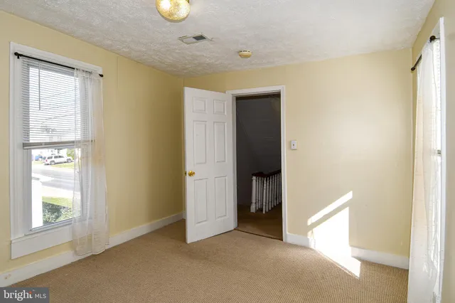 a view of an empty room with window and bathroom