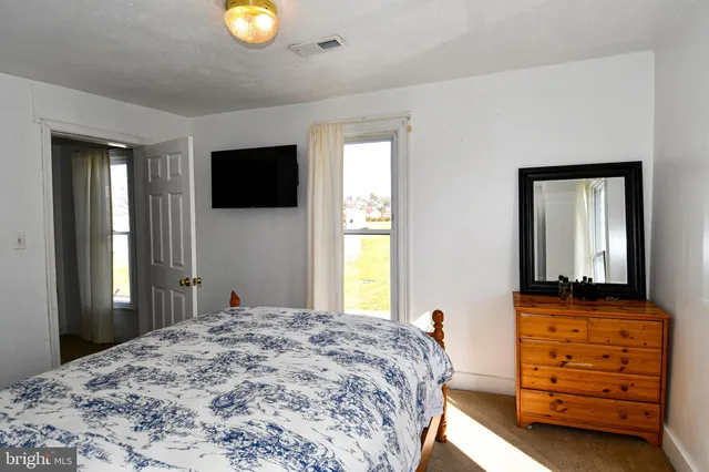 a bedroom with a bed and a flat tv screen on dresser