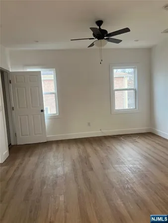 a view of a livingroom with a hardwood floor a ceiling fan and windows