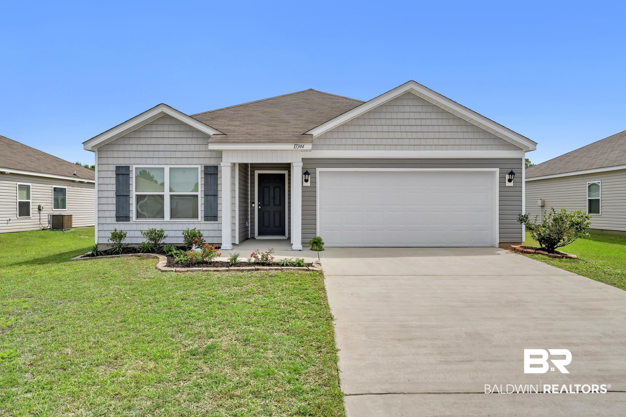 17344 Harding Drive Foley, AL 36535 - Photo 36 of 46 Single-story home featuring a two-car garage, gray siding, a dark paneled front door, decorative window shutters, and a concrete driveway