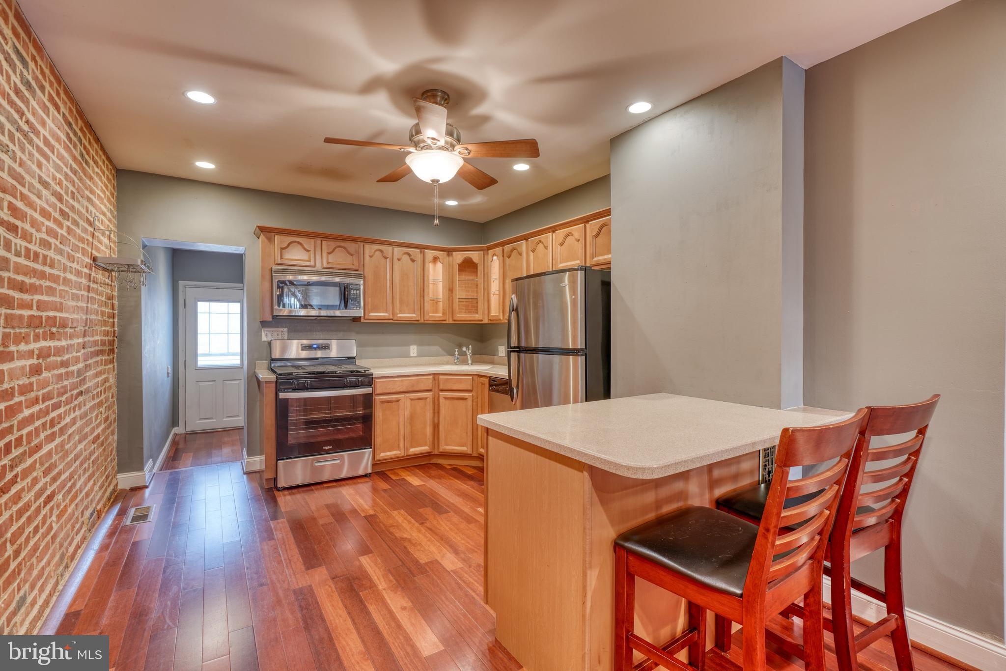 a kitchen with stainless steel appliances kitchen island granite countertop a refrigerator a stove top oven a sink dishwasher and white countertops with wooden floor
