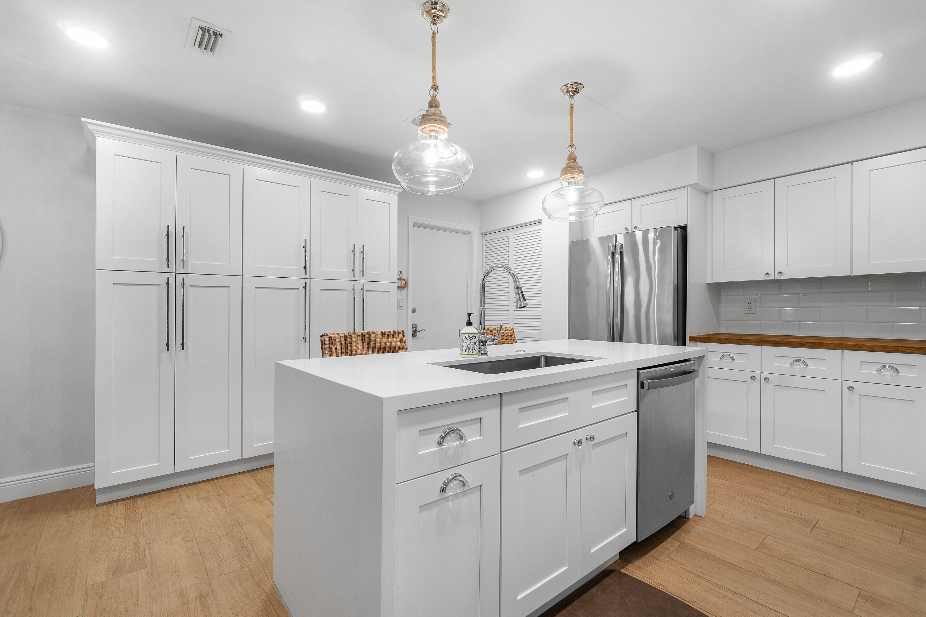 807 Mainsail Circle Jupiter, FL 33477 - Photo 7 of 35 a kitchen with a sink dishwasher and white cabinets with wooden floor