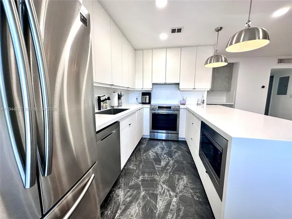 a kitchen with stainless steel appliances granite countertop a refrigerator a sink a stove and white cabinets