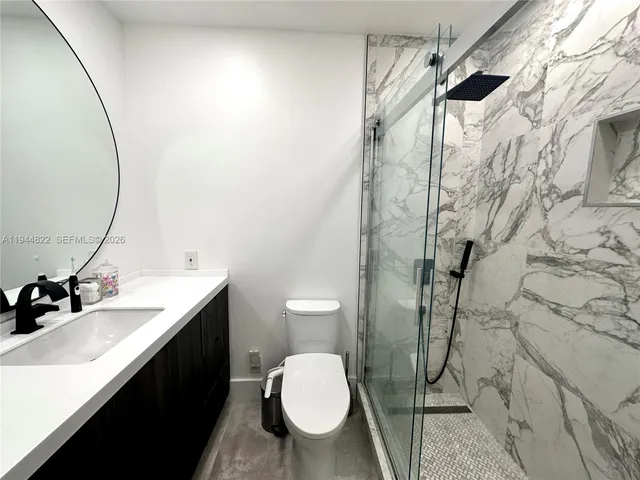 a bathroom with a sink vanity mirror and toilet