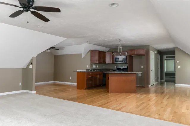 a kitchen with stainless steel appliances kitchen island granite countertop a refrigerator a sink dishwasher a stove and a refrigerator with wooden floor