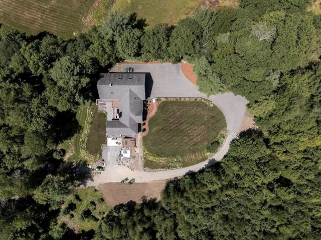 an aerial view of a house with a yard and trees all around