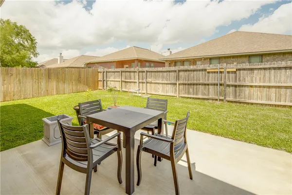 a view of a patio with table and chairs with wooden floor and fence