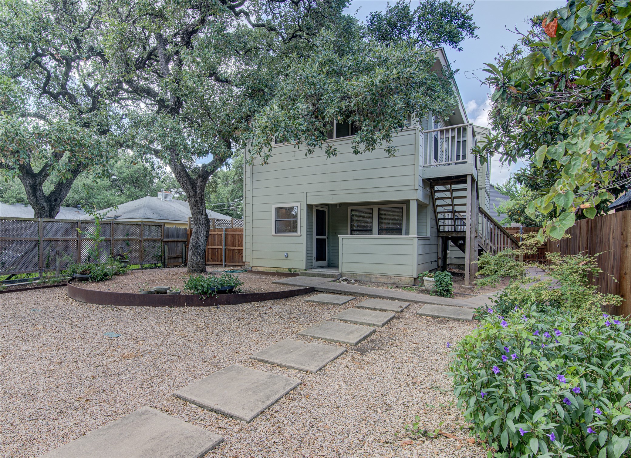 311 West Mary Street Austin, TX 78704 - Photo 32 of 35 Mature trees shade this peaceful private backyard, featuring a gravel patio with stepping stones and verdant garden beds.