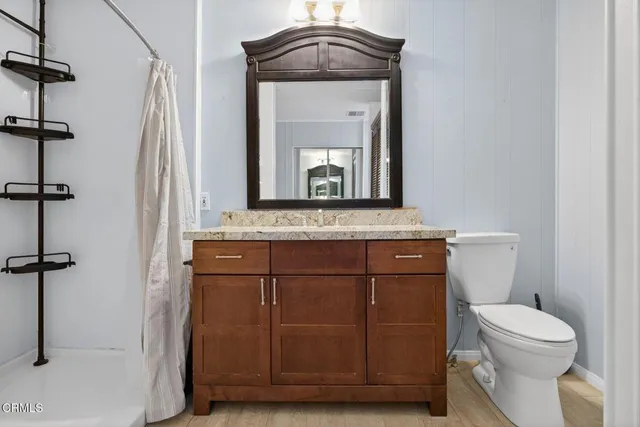a bathroom with a granite countertop sink a mirror and shower