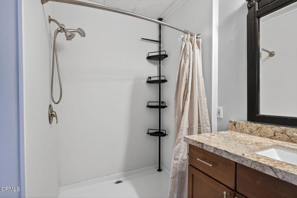 5540 West 5th Street, Unit 111 Oxnard, CA 93035 - Photo 21 of 35 a bathroom with a granite countertop sink a mirror and shower
