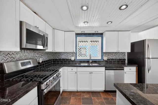 a white kitchen with granite countertop a sink and a stove