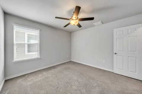 an empty room with windows and fan