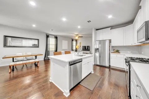 a kitchen with stainless steel appliances white cabinets and wooden floor