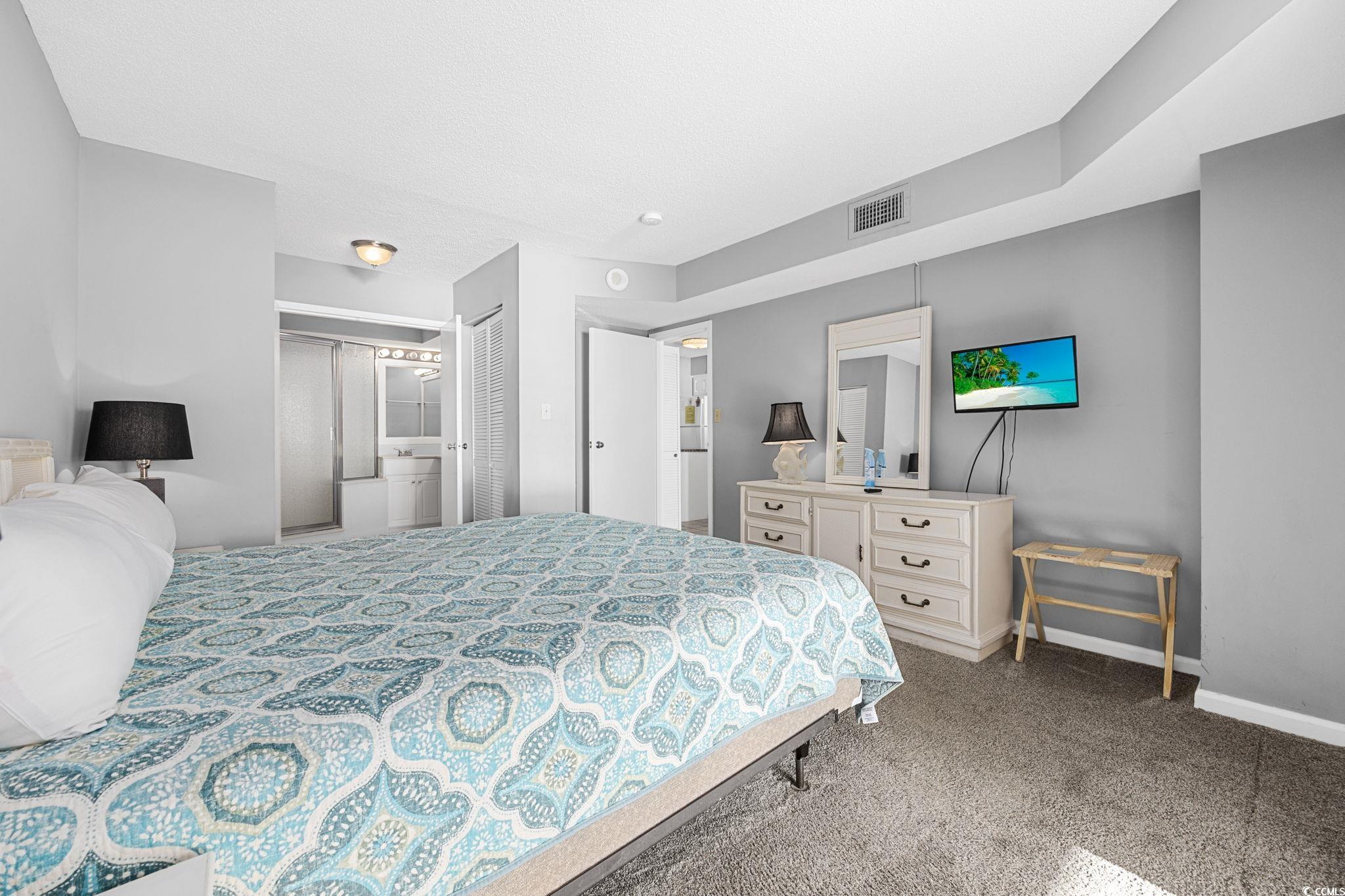 4701 South Ocean Boulevard, Unit 2B North Myrtle Beach, SC 29582 - Photo 18 of 31 Bedroom with light colored carpet, a closet, and ensuite bath