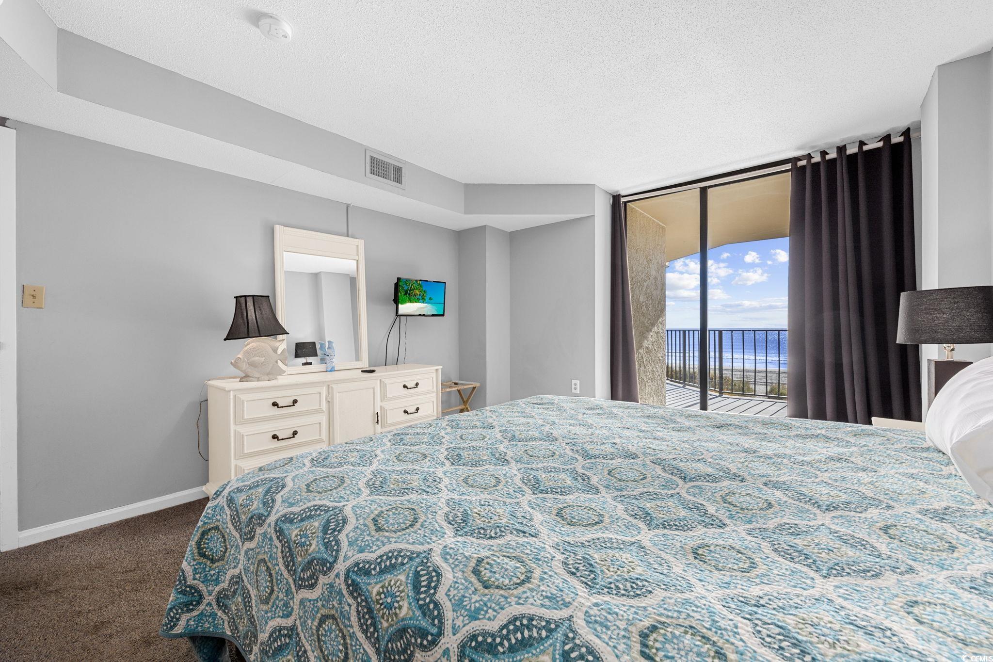 4701 South Ocean Boulevard, Unit 2B North Myrtle Beach, SC 29582 - Photo 19 of 31 Bedroom with a textured ceiling, access to outside, dark carpet, and a wall of windows