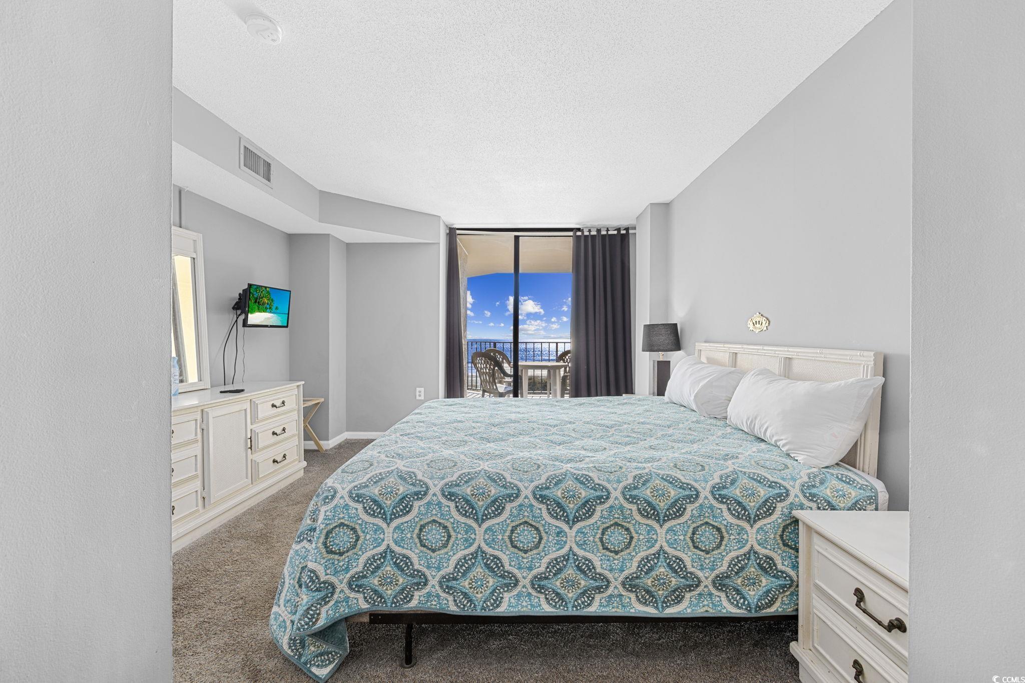 4701 South Ocean Boulevard, Unit 2B North Myrtle Beach, SC 29582 - Photo 20 of 31 Carpeted bedroom featuring floor to ceiling windows, a textured ceiling, and access to outside