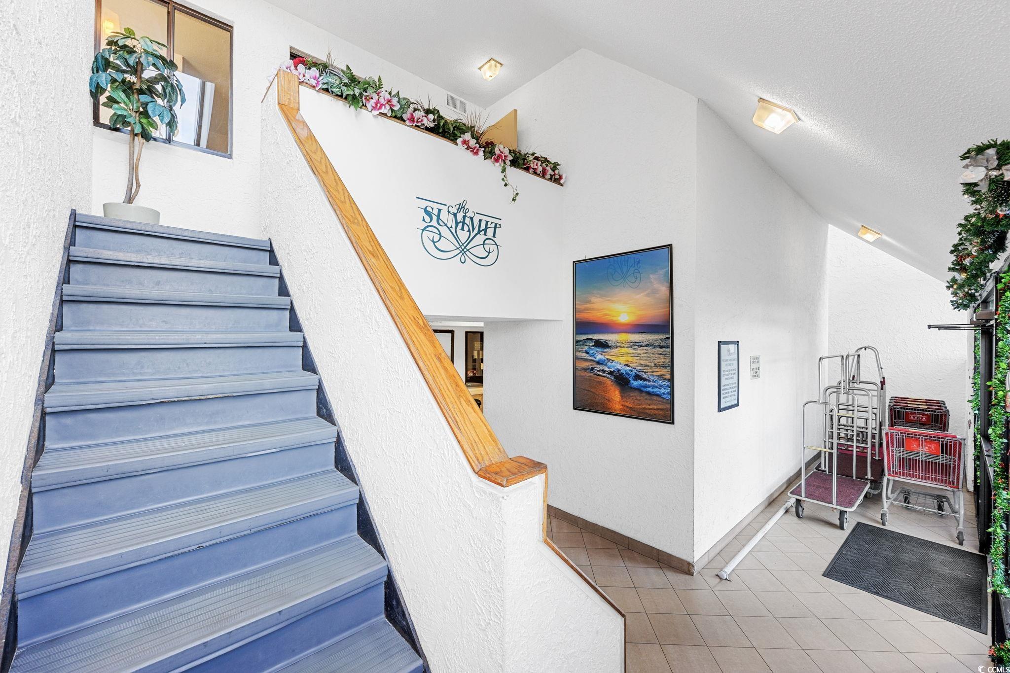 4701 South Ocean Boulevard, Unit 2B North Myrtle Beach, SC 29582 - Photo 3 of 31 Stairs featuring tile patterned floors, a textured wall, vaulted ceiling, and a textured ceiling