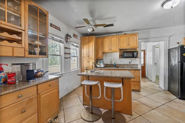 a kitchen with stainless steel appliances granite countertop a refrigerator a sink dishwasher and white cabinets with wooden floor