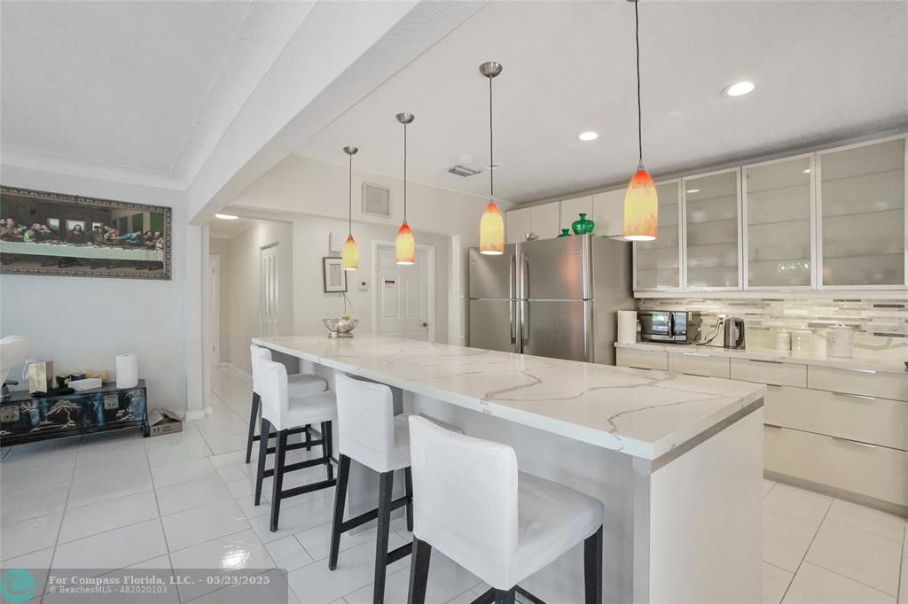1311 Northeast 27th Way Pompano Beach, FL 33062 - Photo 45 of 58 a kitchen with a table chairs refrigerator and microwave