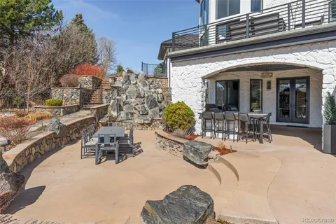 a view of a patio with table and chairs potted plants and a large tree