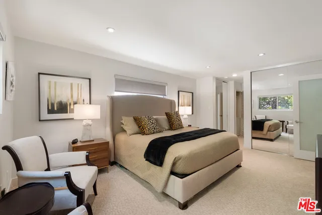 a spacious bedroom with a bed a couch and a view of en suite bathroom