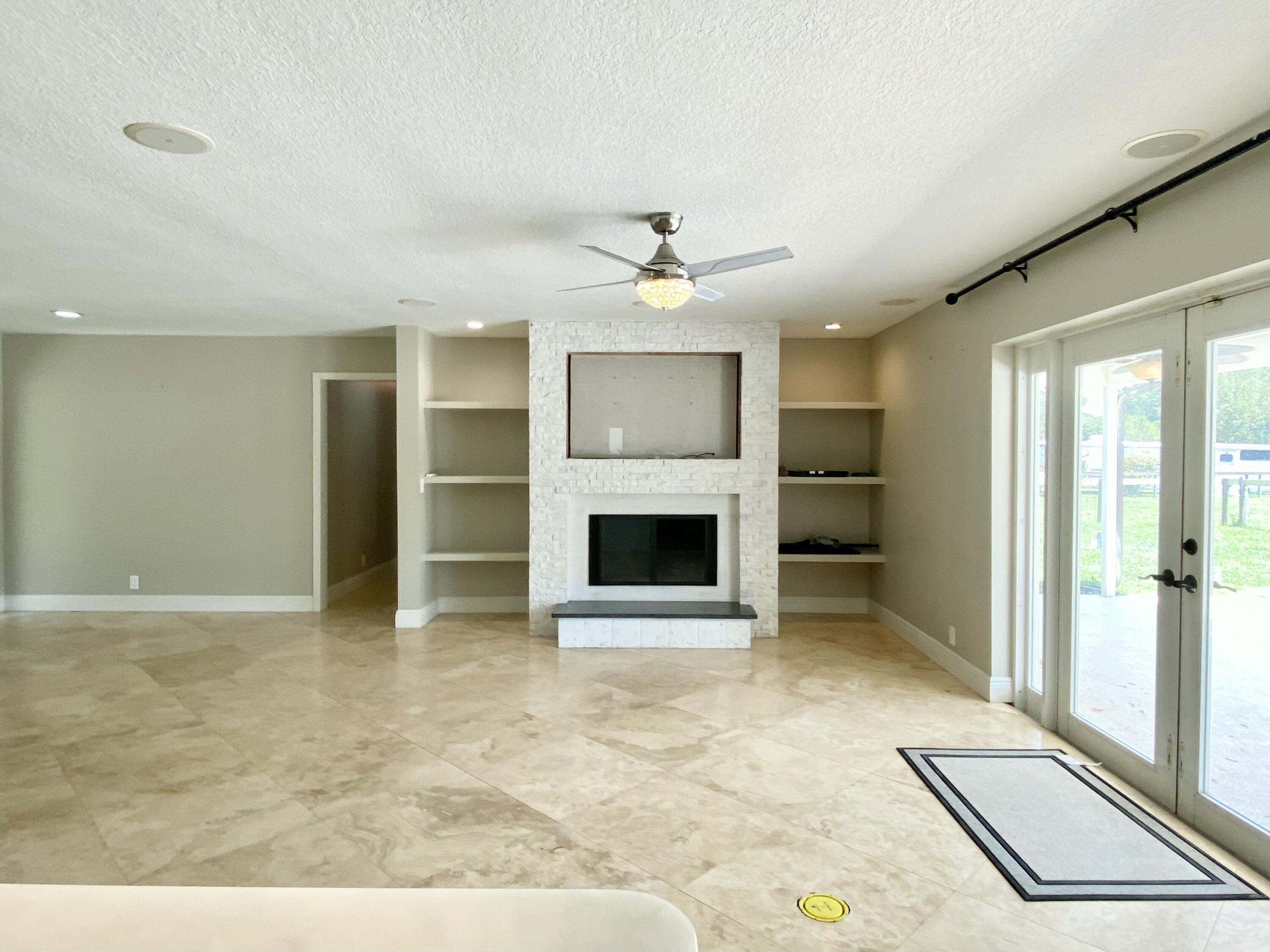 16605 115th Avenue North Jupiter, FL 33478 - Photo 22 of 54 an empty room with a fireplace and a ceiling fan