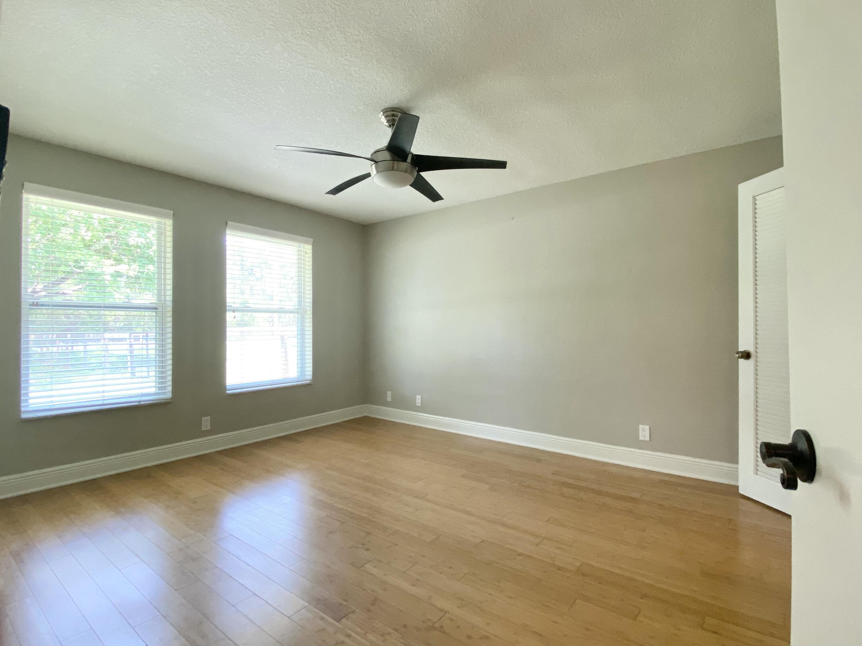 16605 115th Avenue North Jupiter, FL 33478 - Photo 29 of 54 an empty room with wooden floor fan and windows