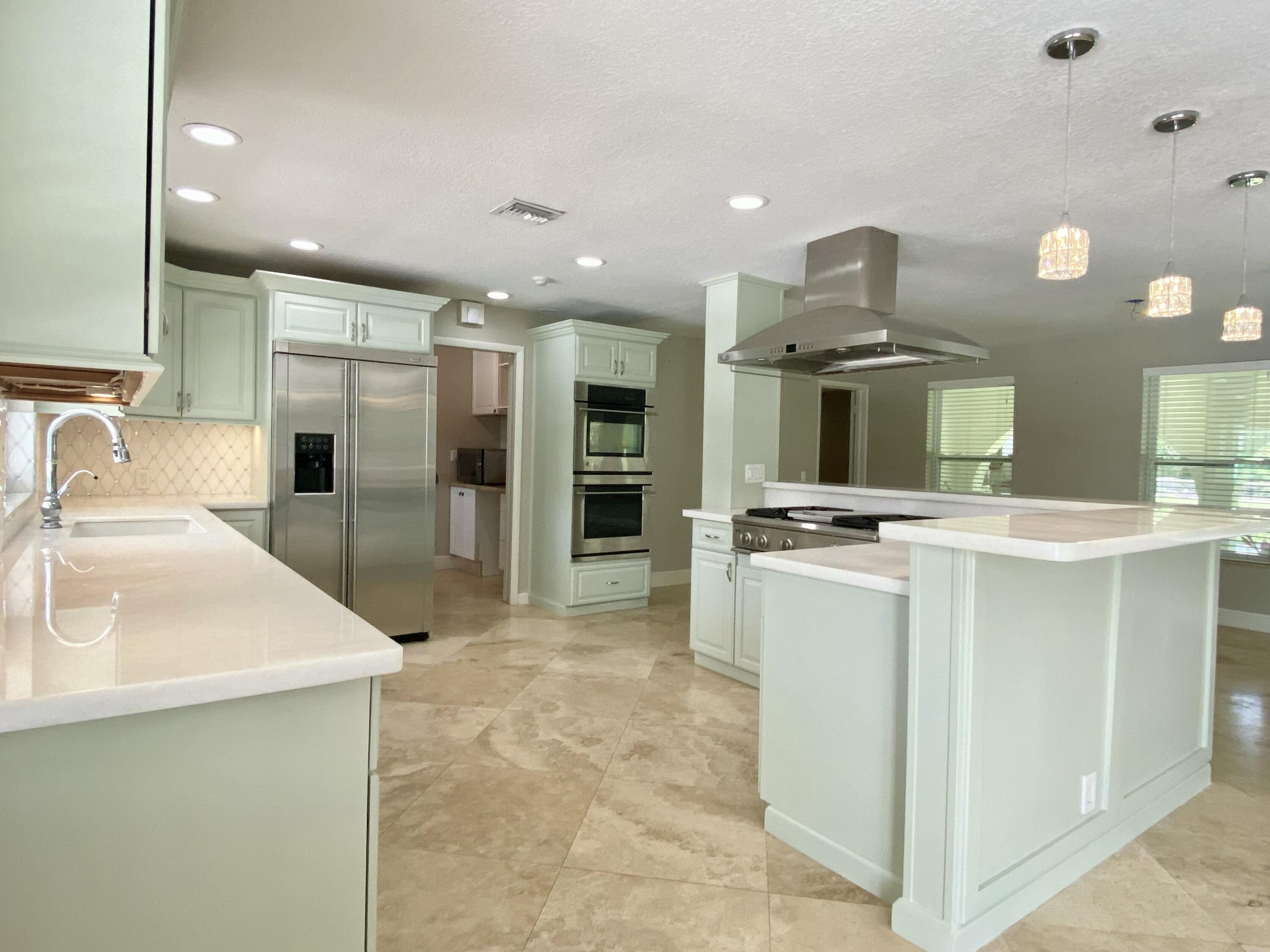 16605 115th Avenue North Jupiter, FL 33478 - Photo 9 of 54 a large white kitchen with a sink stainless steel appliances and cabinets