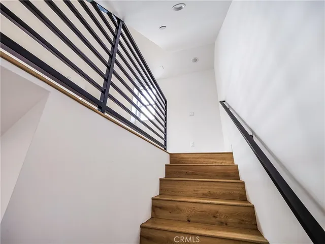 an empty room with wooden floor and kitchen view