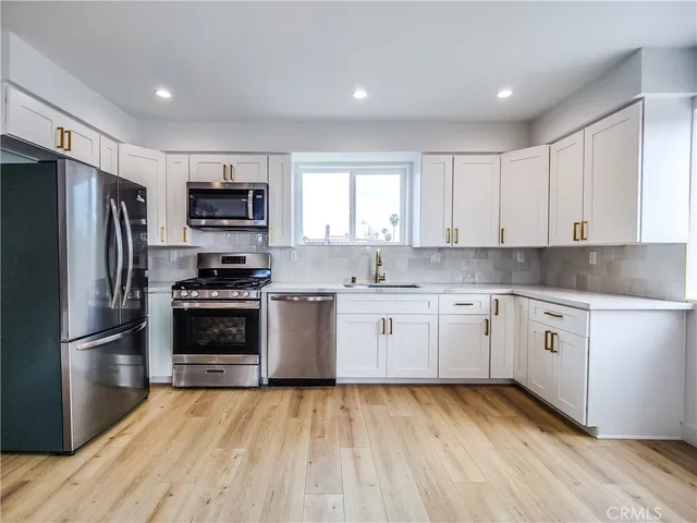 a kitchen with a sink cabinets stainless steel appliances and a window