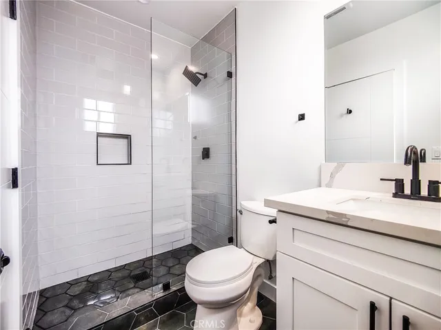 a bathroom with a sink a toilet a mirror and shower