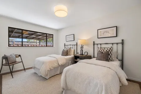 a bedroom with two beds and a large mirror next to a window