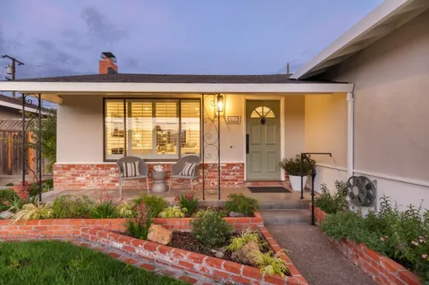 a front view of a house with a yard and potted plants