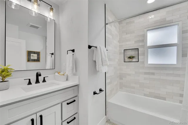 a bathroom with a granite countertop sink a mirror a bathtub and shower