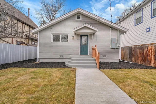 a yellow house with a yard and wooden fence