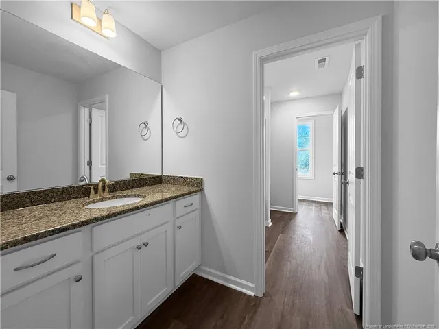 a bathroom with a granite countertop sink and a window