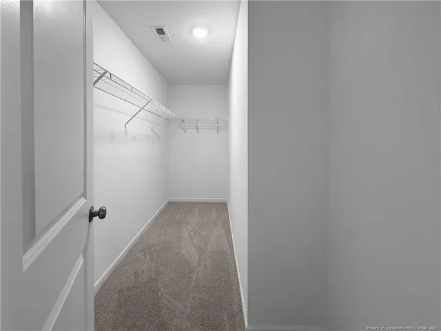 a walk in closet with wooden floor