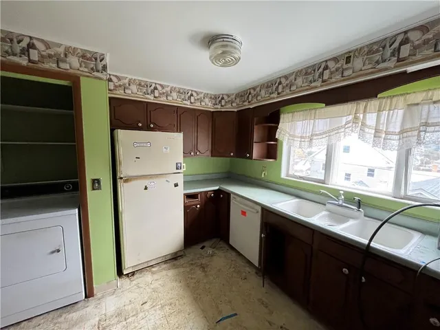 a kitchen with granite countertop a refrigerator a sink a stove and white cabinets