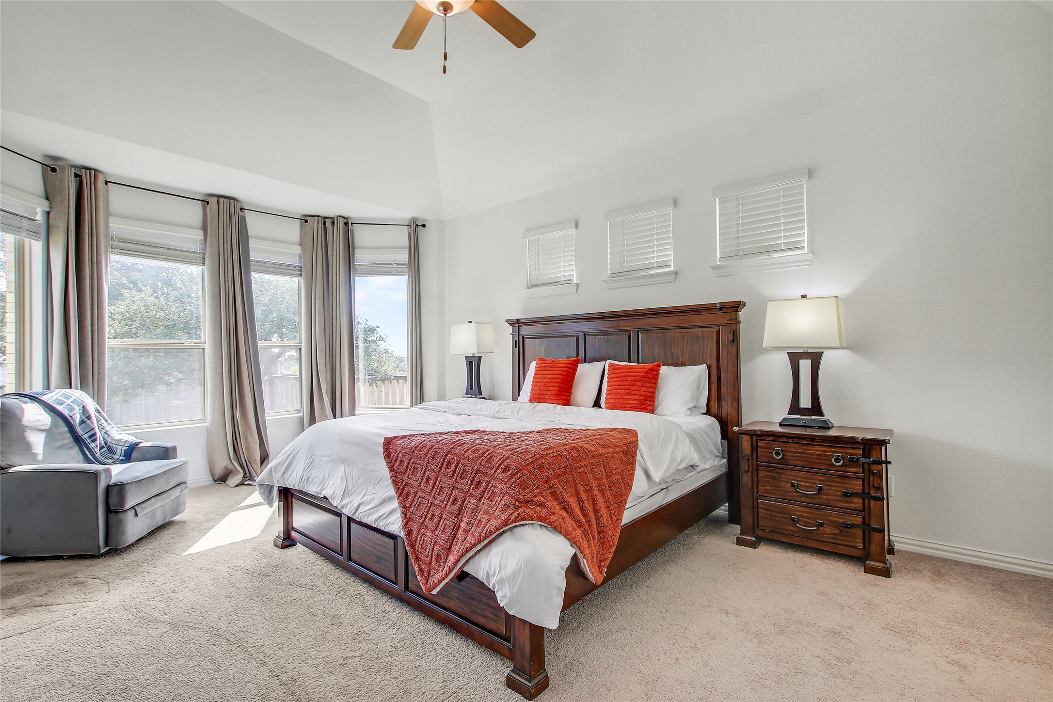 104 Millbend Road Georgetown, TX 78633 - Photo 20 of 40 A spacious primary bedroom features a vaulted ceiling with a fan and a bright bay window overlooking the outdoors.