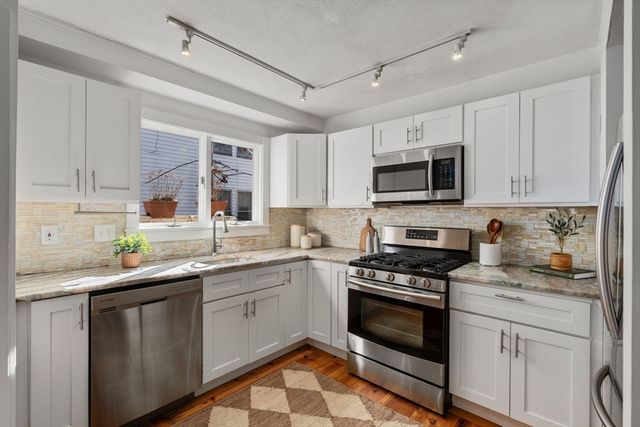 a kitchen with granite countertop a sink a stove and cabinets