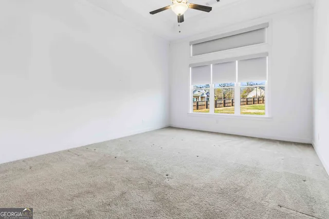an empty room with a chandelier fan and windows