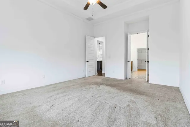 an empty room with chandelier fan and windows