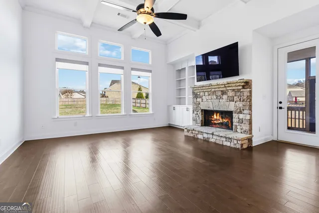 a view of an empty room with wooden floor fireplace and a window