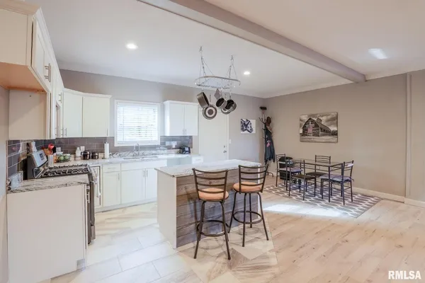 a kitchen with a dining table chairs and white cabinets