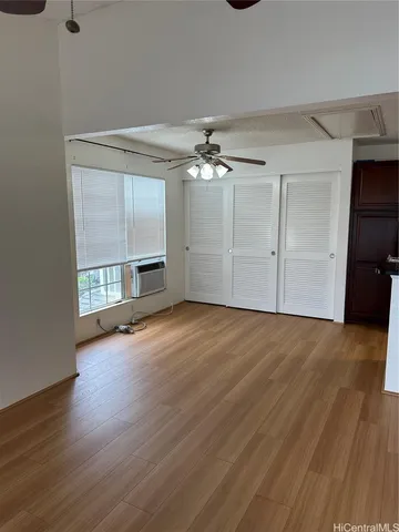an empty room with wooden floor chandelier and windows