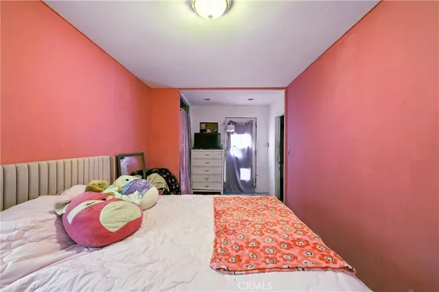 a bedroom with a bed and a dresser next to a window