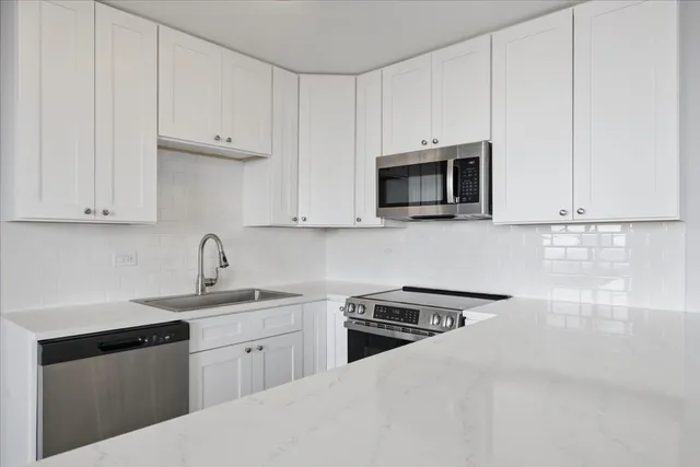 an empty room with wooden floor windows and cabinet