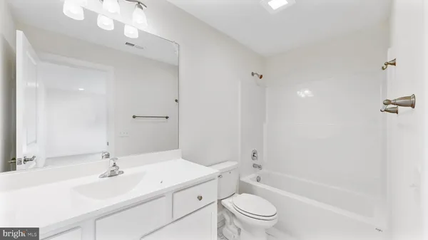 a bathroom with a toilet a sink a mirror a window and vanity