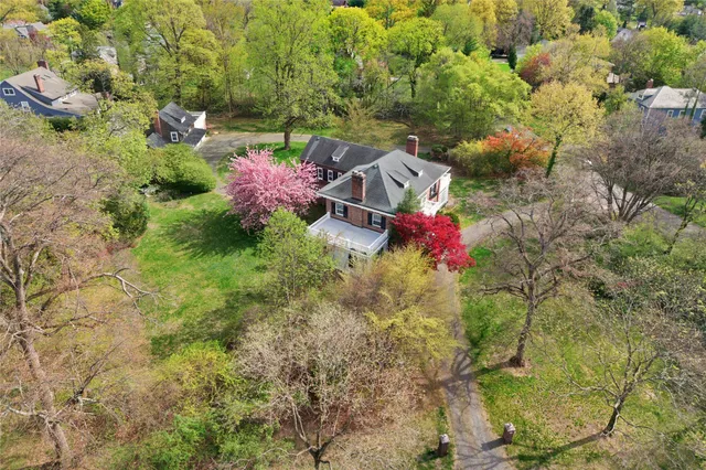 a view of a house with a yard and large trees